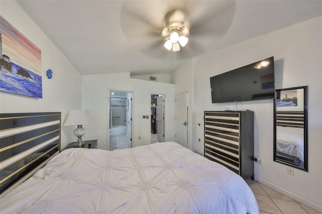 tiled bedroom with ceiling fan, lofted ceiling, a textured ceiling, and ensuite bath