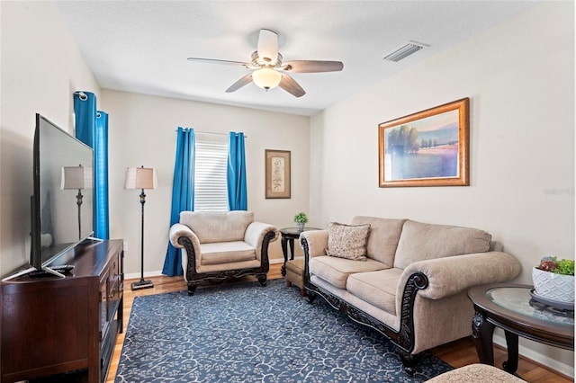 living room featuring ceiling fan and dark hardwood / wood-style flooring