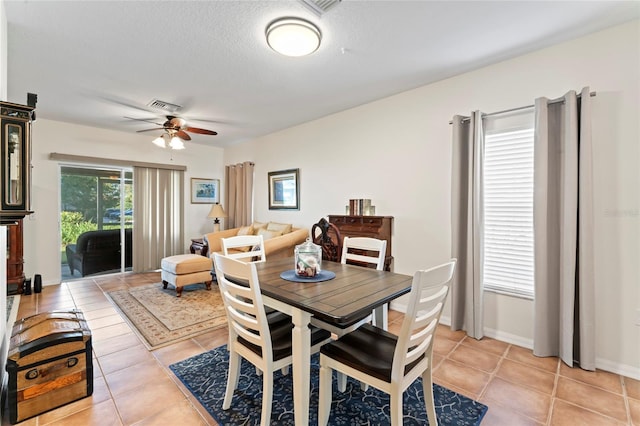 tiled dining area with a textured ceiling and ceiling fan