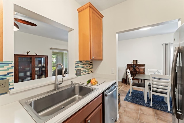 kitchen with sink, light tile patterned floors, ceiling fan, appliances with stainless steel finishes, and backsplash