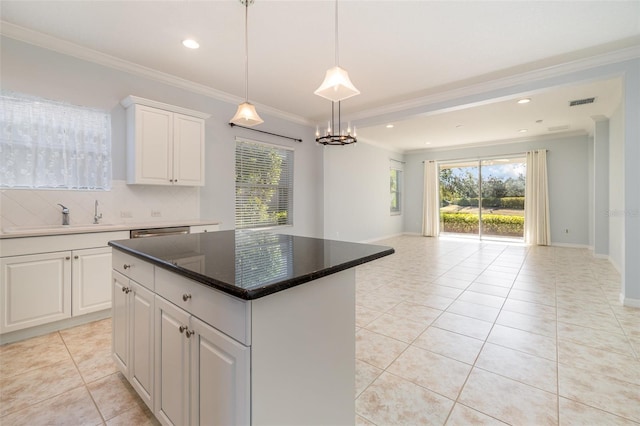 kitchen with light tile patterned flooring, white cabinets, backsplash, a center island, and a healthy amount of sunlight