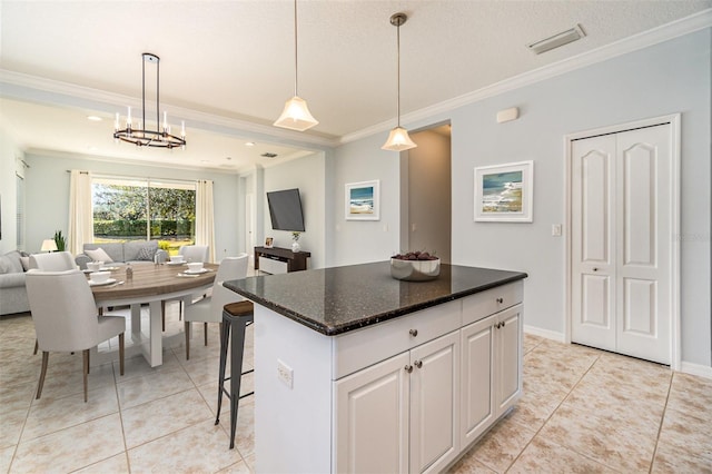 kitchen featuring a breakfast bar, hanging light fixtures, ornamental molding, a kitchen island, and white cabinets