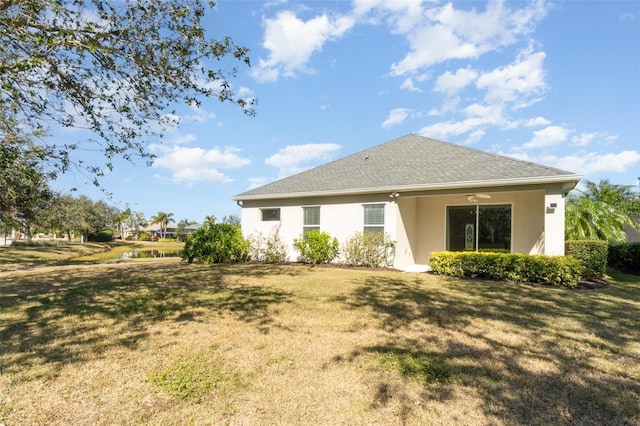 rear view of property with ceiling fan and a yard