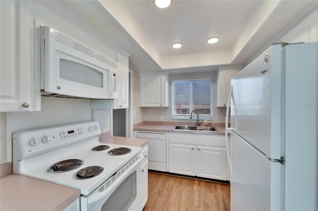 kitchen featuring sink, white cabinetry, light wood-type flooring, a raised ceiling, and white appliances