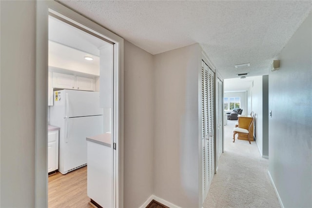 hallway featuring light carpet and a textured ceiling