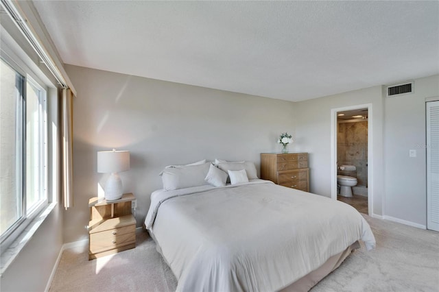 carpeted bedroom featuring connected bathroom and a textured ceiling