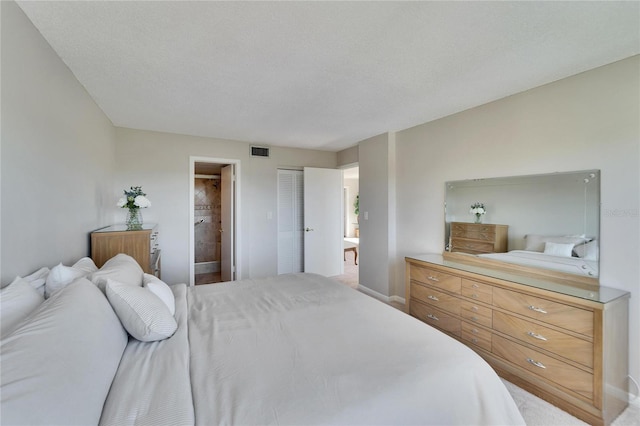 bedroom featuring ensuite bathroom and a textured ceiling