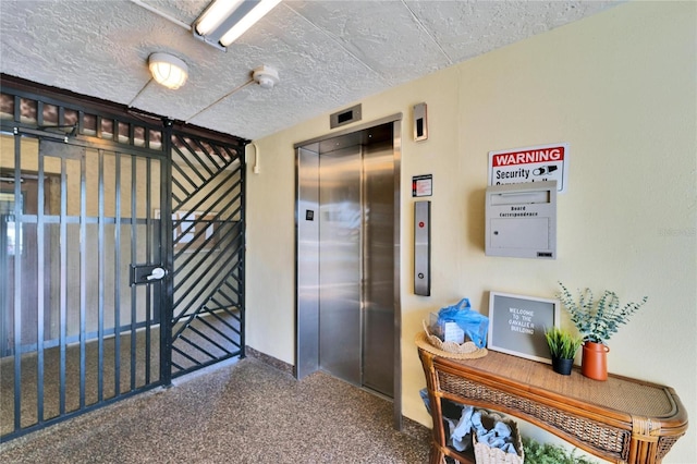 corridor featuring elevator, carpet flooring, and a textured ceiling