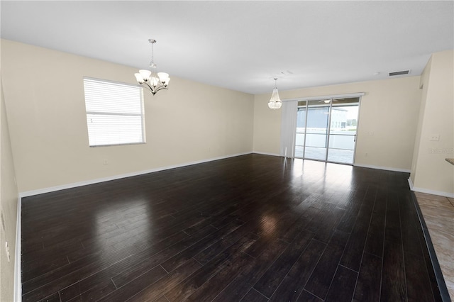 spare room featuring dark hardwood / wood-style floors and a chandelier