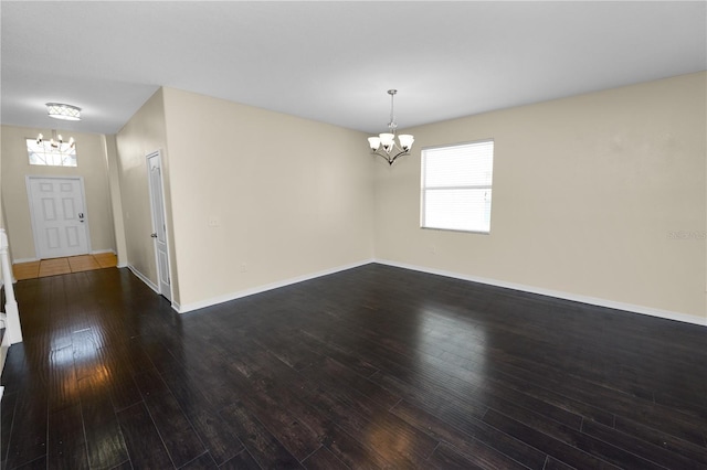 unfurnished room with an inviting chandelier and dark hardwood / wood-style flooring