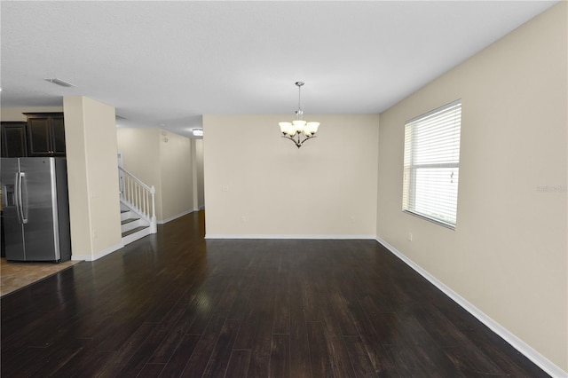 spare room featuring a chandelier and dark hardwood / wood-style flooring