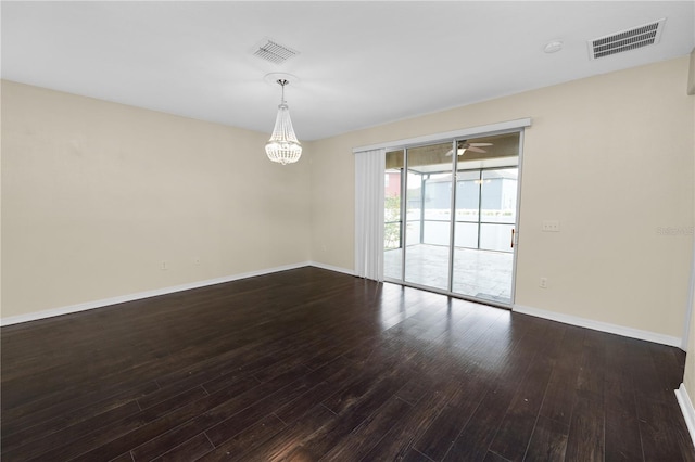 empty room with ceiling fan with notable chandelier and dark hardwood / wood-style floors