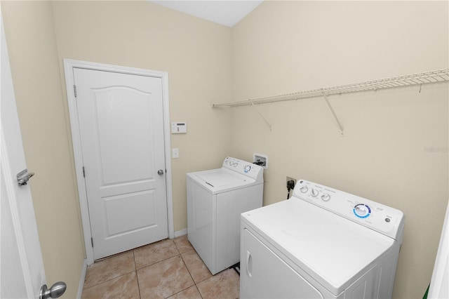 clothes washing area with washer and dryer and light tile patterned floors