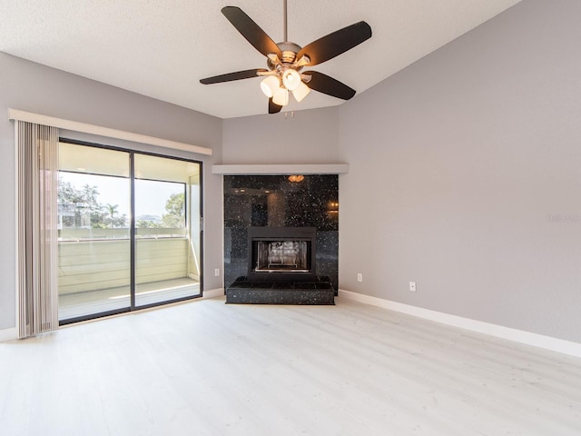 unfurnished living room with a textured ceiling, light hardwood / wood-style floors, a tile fireplace, and ceiling fan