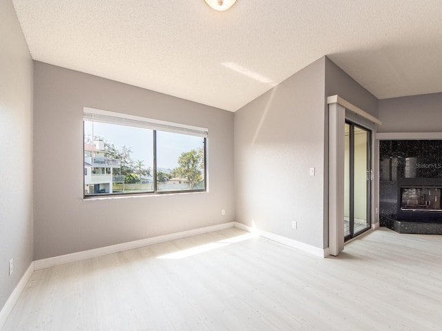 unfurnished room with light hardwood / wood-style flooring and a textured ceiling