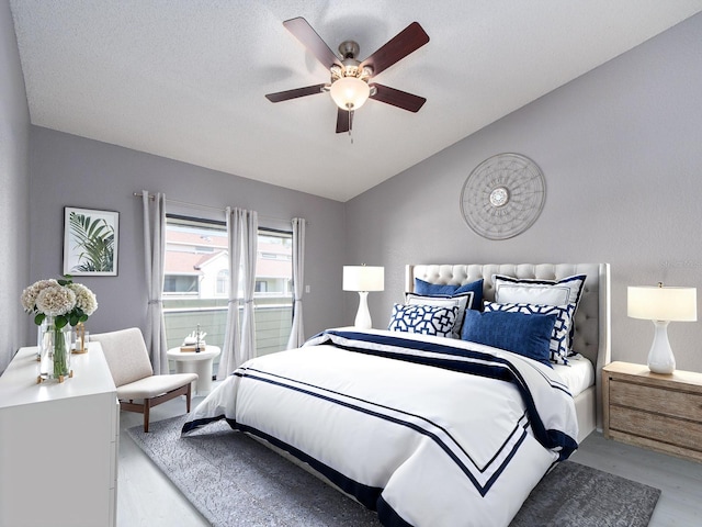 bedroom with ceiling fan, vaulted ceiling, and light wood-type flooring