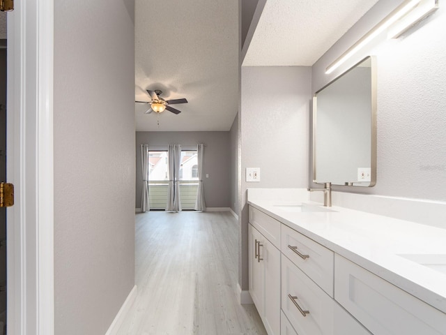 bathroom featuring vanity, ceiling fan, hardwood / wood-style flooring, and a textured ceiling