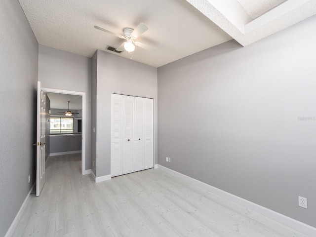 unfurnished bedroom featuring ceiling fan, light hardwood / wood-style floors, a closet, and a textured ceiling