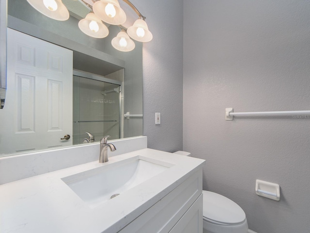 bathroom featuring vanity, toilet, and a shower with shower door