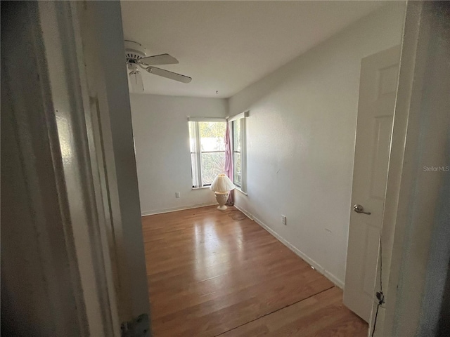 empty room with ceiling fan and light hardwood / wood-style flooring