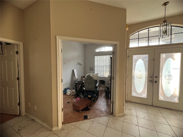 entryway featuring french doors, a towering ceiling, and light tile patterned floors