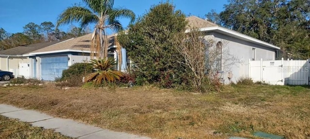 view of side of property featuring a garage and a lawn