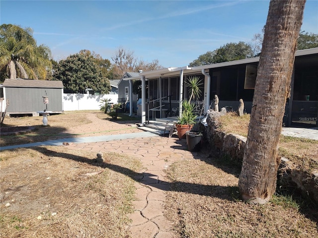 view of yard featuring a storage shed, a patio area, and a sunroom