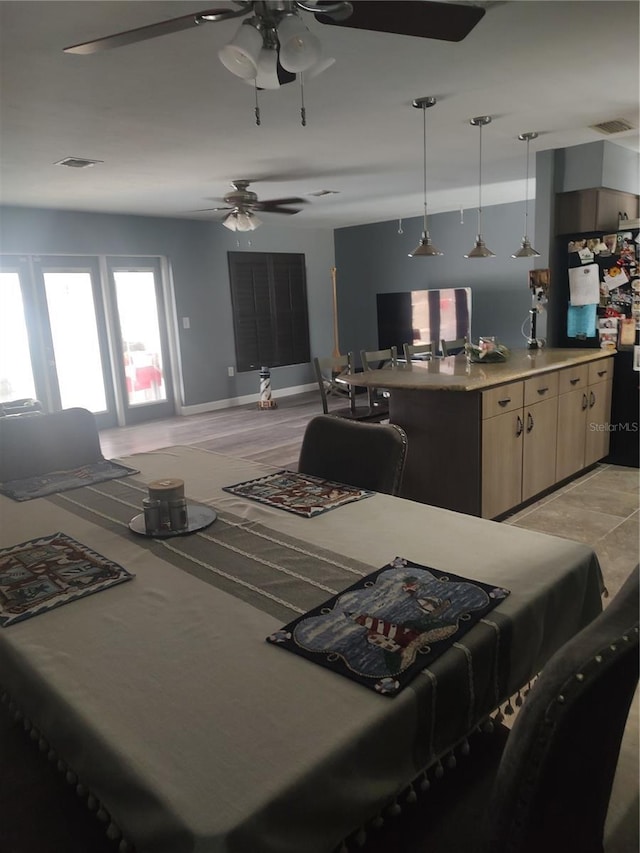 kitchen with pendant lighting, black refrigerator, ceiling fan, and light brown cabinets