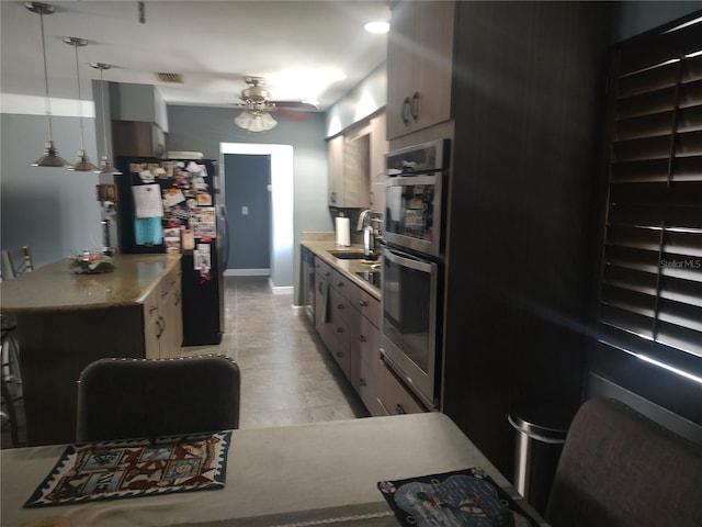 kitchen with ceiling fan, stainless steel double oven, decorative light fixtures, and sink