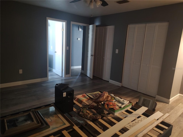 bedroom with ceiling fan, wood-type flooring, and multiple closets