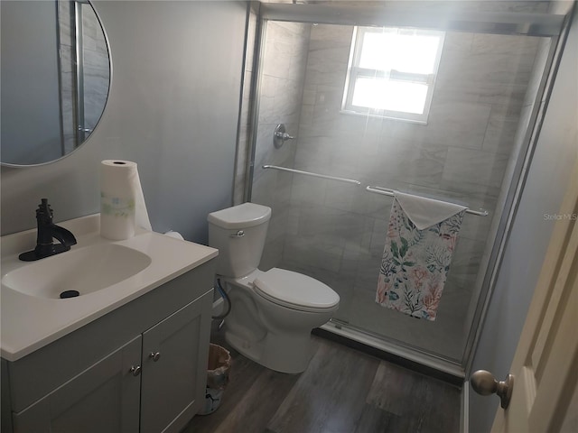 bathroom with an enclosed shower, wood-type flooring, vanity, and toilet