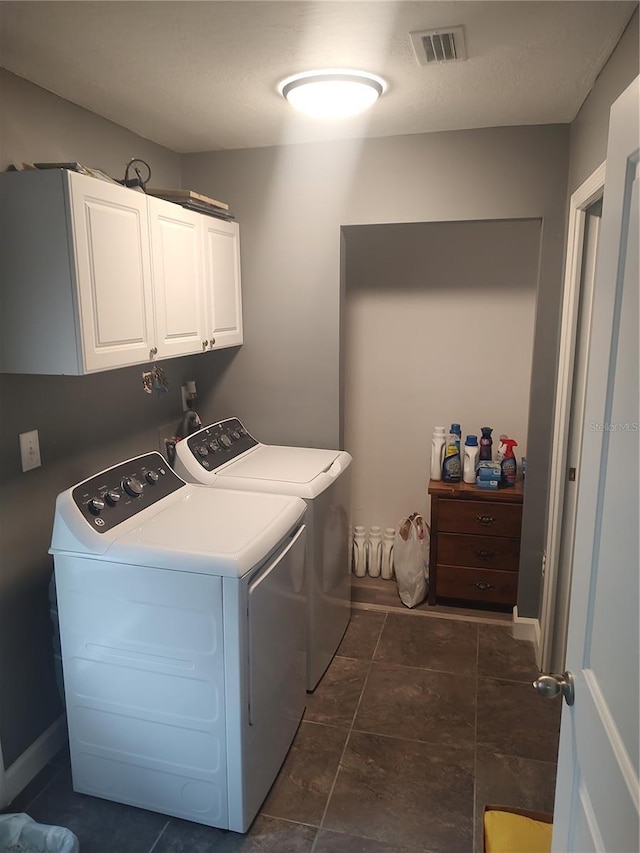 clothes washing area featuring cabinets and washing machine and clothes dryer