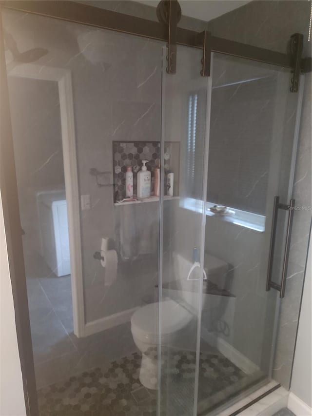 bathroom with tile patterned flooring, a shower with door, and toilet