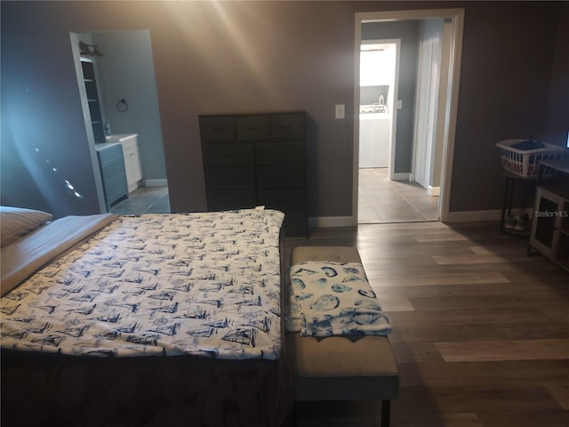 bedroom with washer / clothes dryer, ensuite bathroom, and light hardwood / wood-style floors