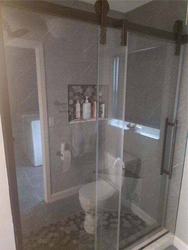 bathroom with toilet, a shower with shower door, and tile patterned flooring