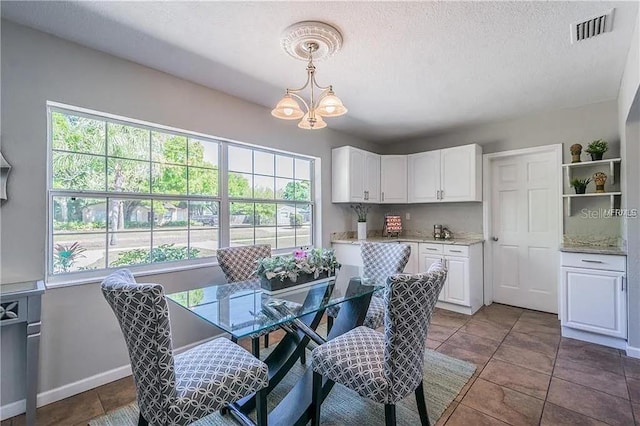 dining area with tile patterned flooring, a textured ceiling, and a chandelier