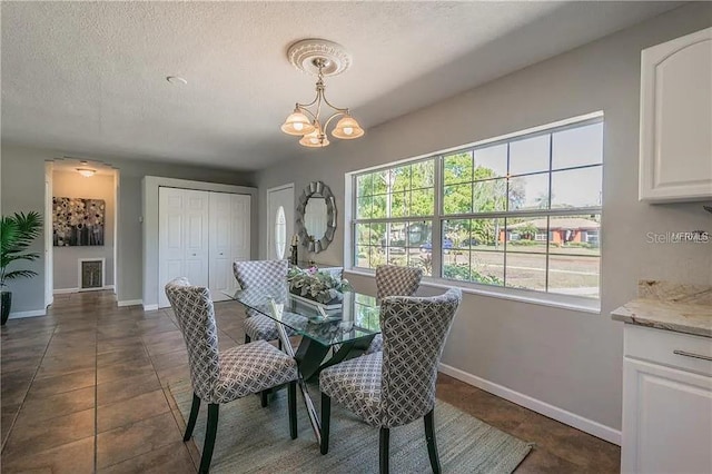 dining room with dark tile patterned floors, a notable chandelier, and a textured ceiling