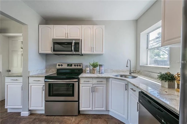 kitchen featuring stainless steel appliances, white cabinetry, light stone countertops, and sink