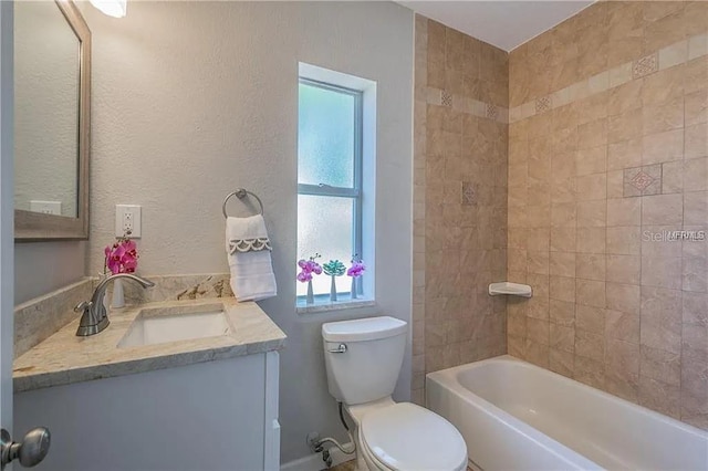 full bathroom with tiled shower / bath, vanity, and toilet