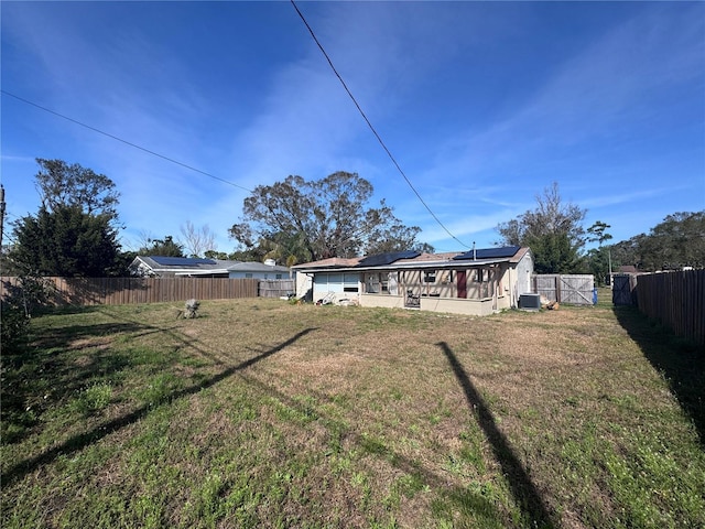 back of property featuring cooling unit, a lawn, and solar panels