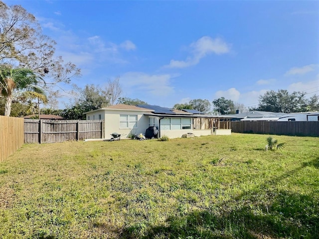 rear view of property with a lawn and solar panels