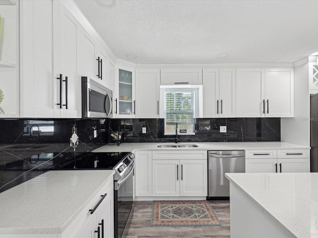 kitchen featuring light stone counters, sink, stainless steel appliances, and white cabinets