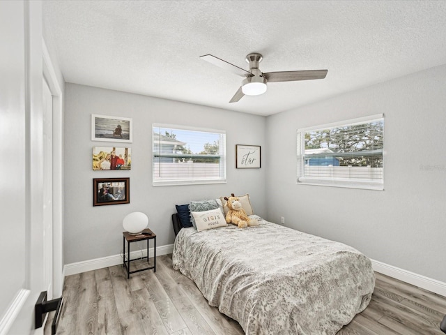 bedroom featuring ceiling fan, light hardwood / wood-style flooring, and a textured ceiling