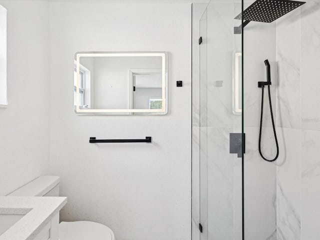 bathroom with vanity, toilet, and a shower with door