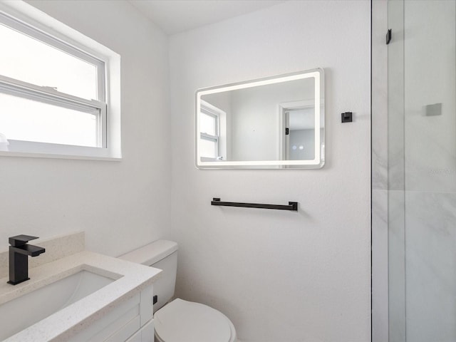 bathroom featuring vanity, toilet, and a healthy amount of sunlight