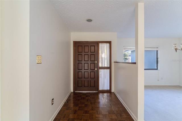 foyer with dark parquet floors and a textured ceiling