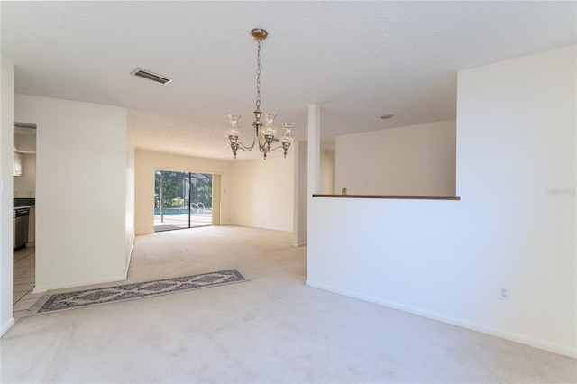 carpeted empty room with a textured ceiling and an inviting chandelier