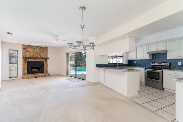 kitchen featuring stainless steel electric range, hanging light fixtures, white cabinets, light colored carpet, and kitchen peninsula