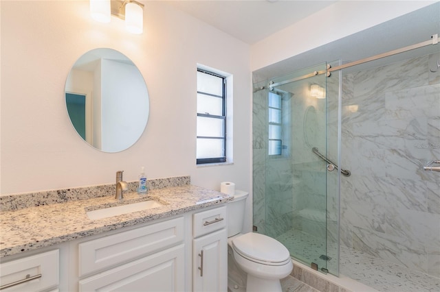 bathroom featuring a shower with door, vanity, and toilet