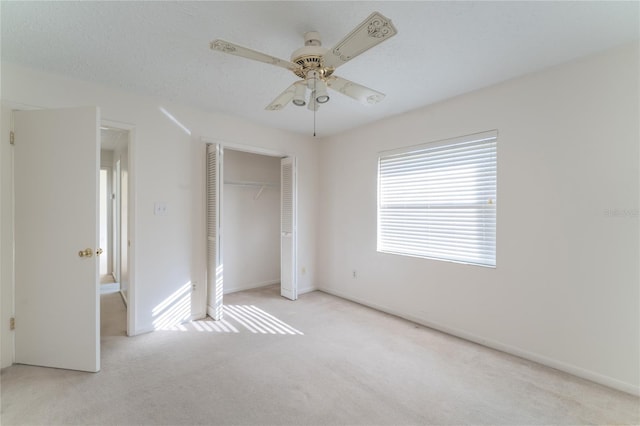 unfurnished bedroom with ceiling fan, light colored carpet, a closet, and a textured ceiling